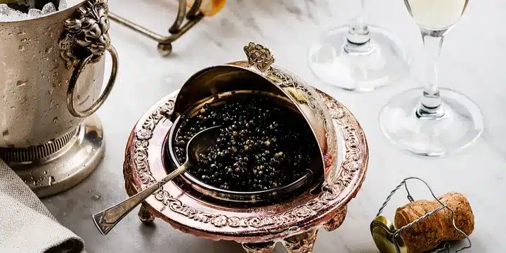 Caviar, also known as fish eggs or roe, is a delicacy that has been enjoyed by humans for centuries. It is commonly associated with luxury and high-end dining, but there is much more to caviar than meets the eye. In this blog post, we will explore 9 fascinating facts about caviar that you may not have known. FACT ONE The most expensive food in the world is Almas caviar from the Iranian Beluga fish. Known as “black gold” it regularly sells for around £20,000 (US$26,420) per kilogram, according to Guinness World Records. FACT TWO Almas are eggs from rare albino sturgeon that are 60 to 100 years old. FACT THREE The traditional way to eat caviar is on the skin between the index finger and the thumb. If that is not suitable, caviar tastes better from a spoon made from bone, crystal, or mother-of-pearl, as metal spoons can alter the taste. The eggs should be rolled slowly around the mouth until they pop and release flavor. FACT FOUR Although caviar is a symbol of opulence and affluence – and historically the food of kings – the lack of concerns over overfishing in the early 1900s meant there was an abundance of it in the US. At that time, it was often offered as a free snack with a beer in bars around the world. It was usually the cheaper, saltier types of caviar that were served as the salt made drinkers thirstier and encouraged people to drink more.. FACT FIVE Eggs from only three types of sturgeon – Beluga, Osetra, and Sevruga – can be called caviar. FACT SIX Caviar from China is now considered the best in the world and is the choice of top chefs from Alain Ducasse to Joël Robuchon. FACT SEVEN The best quality – and most expensive – caviar has larger eggs that are lighter in color. The eggs are also older. Eggs of lesser quality do not have such an intense fishy flavor. FACT EIGHT Goodbye Viagra, hello caviar. It is said the “black pearls” are a good remedy for impotence. You will not know until you try. FACT NINE Feeling down? Reach for a tin of caviar. The ancient Greeks and Romans swore it cured depression. Scientific studies show that high doses of omega-3 – which caviar has an abundance of – are helpful for conditions such as depression. Vitamin A in caviar is good for eyesight and calcium helps strengthen bones. It is also said that caviar helps improve our immune system. Caviar Facts: 9 fascinating facts about Caviar