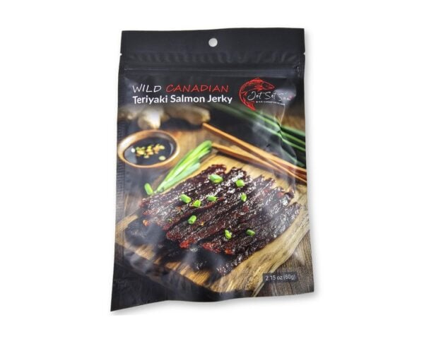 Pouch of Wild Canadian Teriyaki Salmon Jerky, showing slices on a wooden board with green garnish (brand Jet Set).